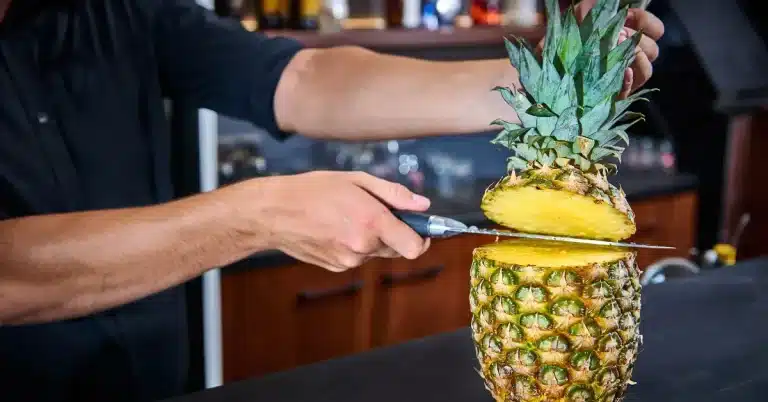 her ses en mand skære en ananas over