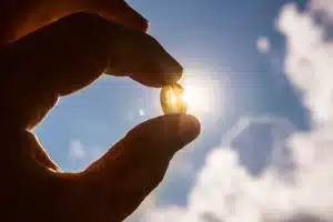 d-vitamin mangel angst. Billede af mand der holder en vitamin pille op mod solen