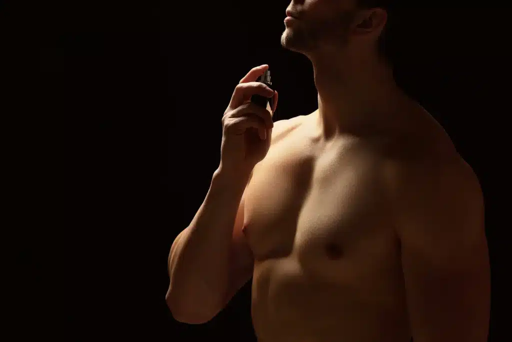 BIllede af en ung mand der sprøjter parfume på sig selv